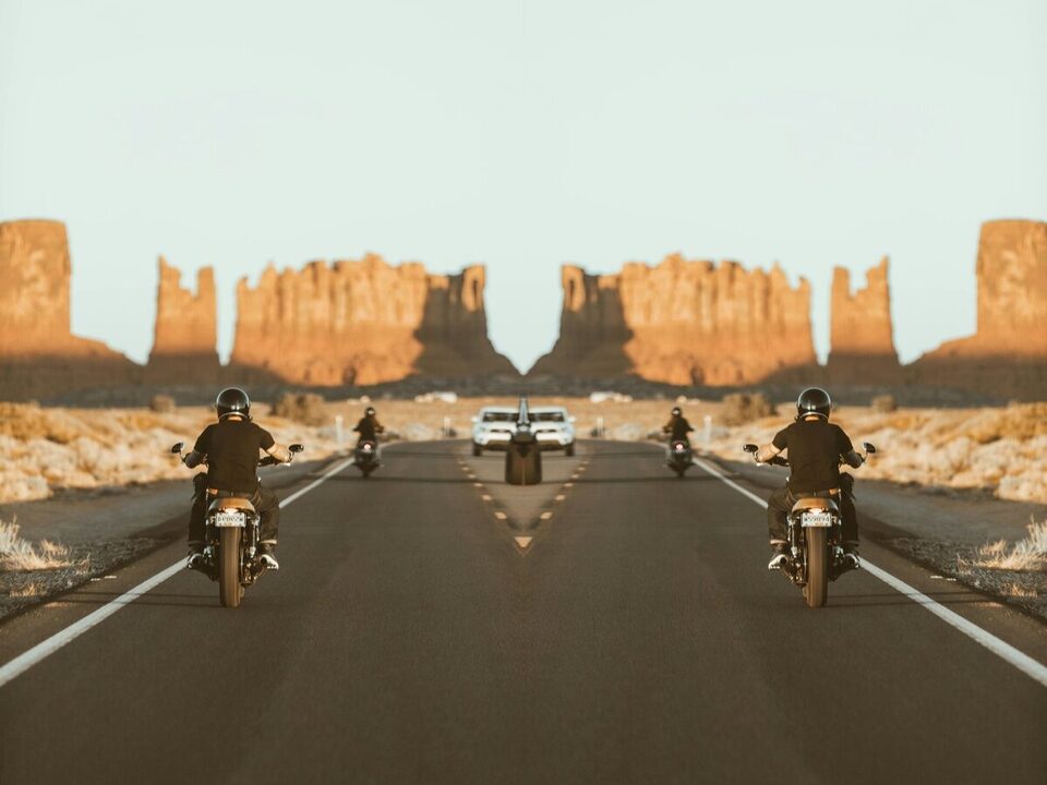 Two motorcyclists riding a desert highway toward red rock buttes at golden hour — OnPoint Utah Motorcycle Insurance.