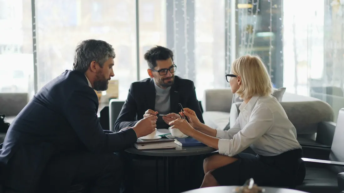 Three business professionals meeting at a table reviewing documents