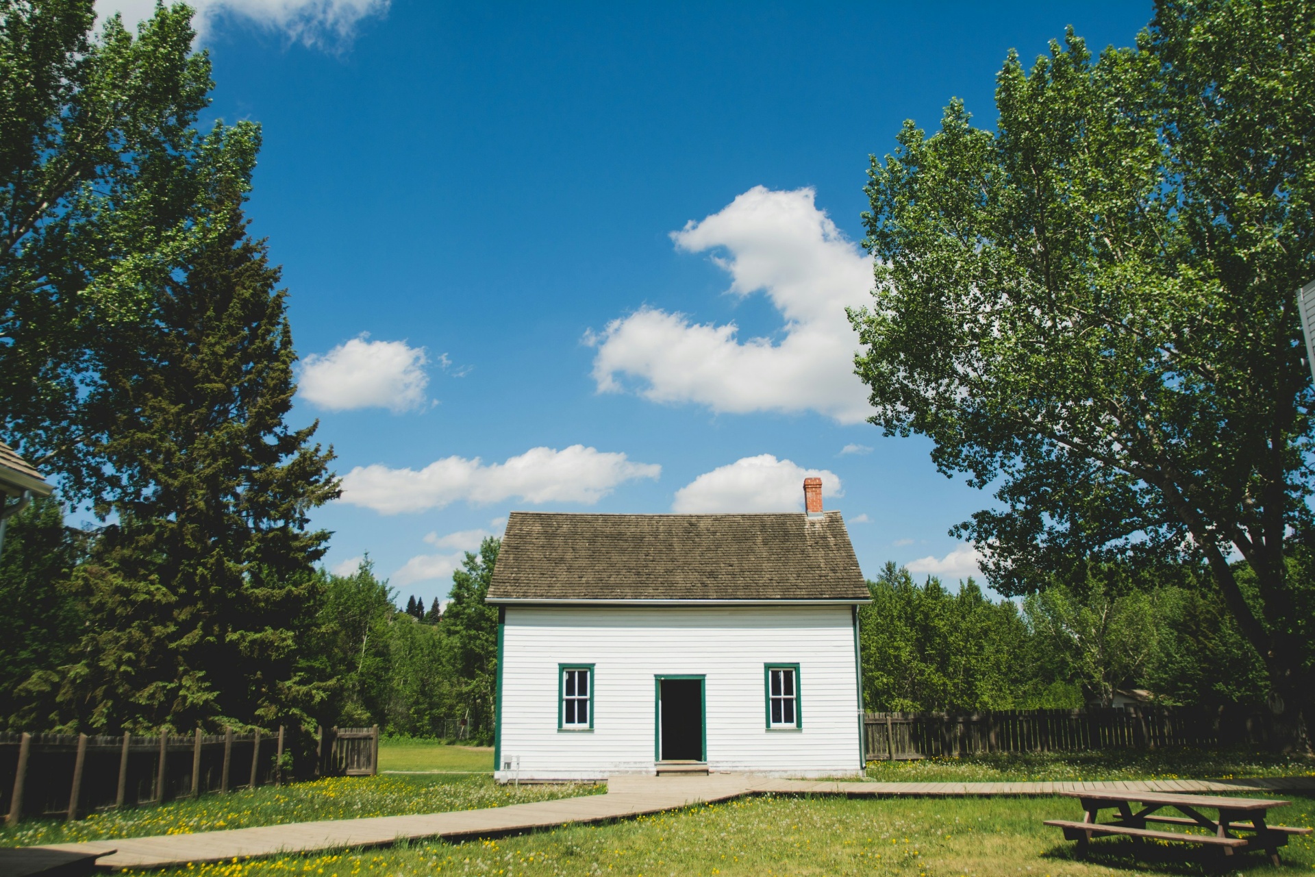 White farmhouse under a wide blue sky — Enterprise, UT is small-town ranch country at 5,300 ft