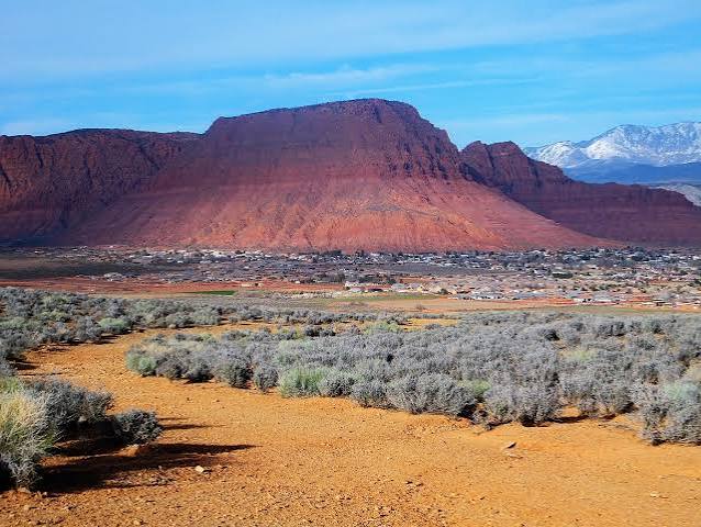 Red Mountain rising above Ivins, Utah with snow-capped Pine Valley peaks in the distance