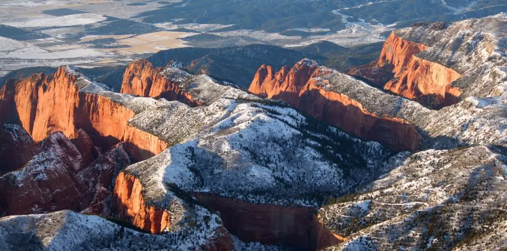 Aerial view of snow-dusted Kolob Canyons red rock fins above Southern Utah farmland near Cedar City