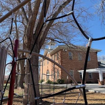 Historic Washington Elementary brick schoolhouse seen through playground equipment