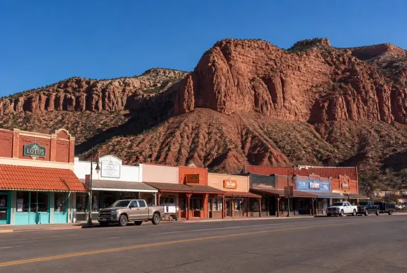 Main Street storefronts in Kanab, Utah beneath the red sandstone Vermilion Cliffs — free ACA health insurance enrollment for Kane County households in 84741