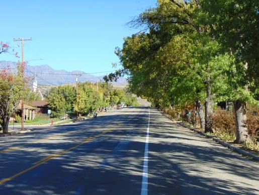 Main Street in Toquerville, Utah lined with cottonwoods and shade trees with the Pine Valley Mountains on the horizon — the garaging address that shapes 84774 auto premiums