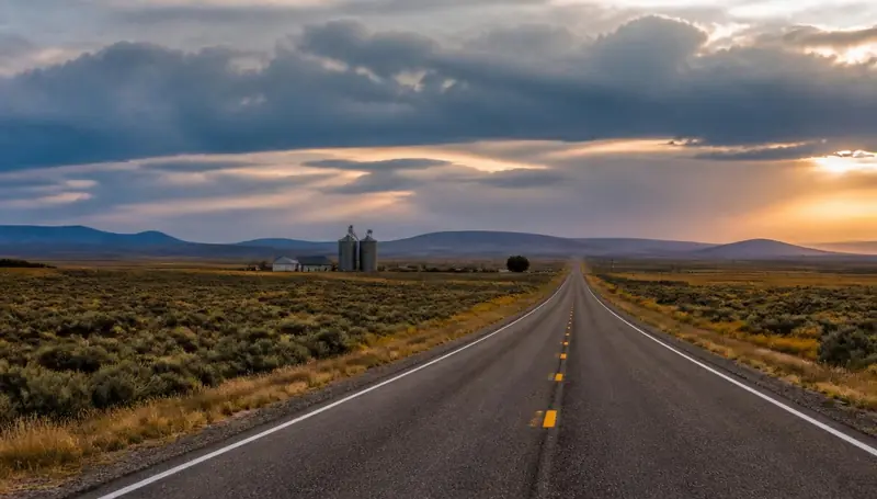 Two-lane highway running past silos and fields on the edge of Enterprise, Utah — health insurance and ACA Marketplace enrollment for Enterprise, Utah 84725 households