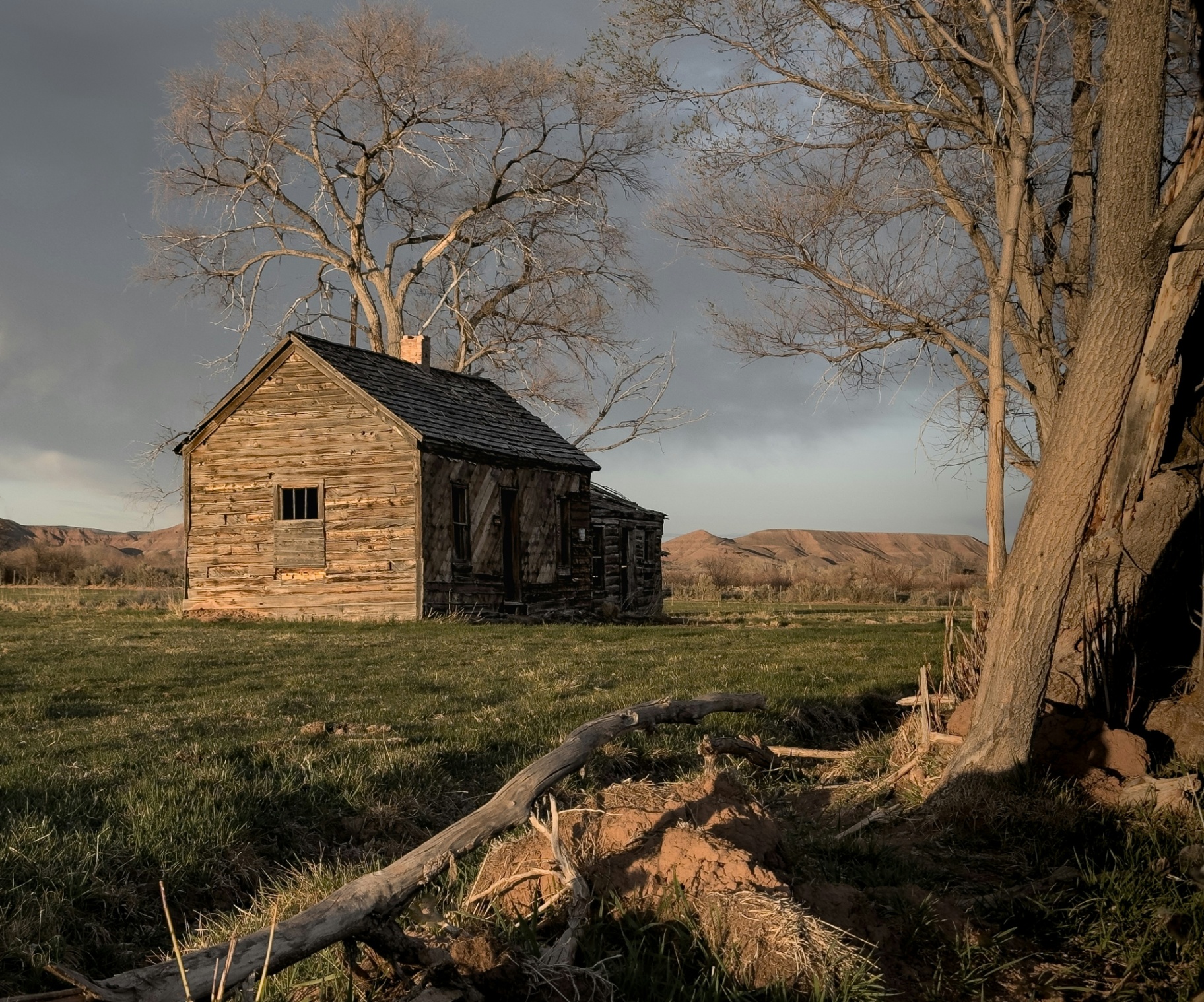 Rustic weathered wood cabin at golden hour in Grass Valley near Pine Valley, Utah with cottonwoods and distant sandstone ridges — the older-cabin rebuild profile and outbuilding exposure that carriers rate into every 84781 homeowners insurance quote