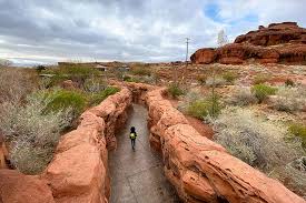 Hiker on a slot-canyon trail through red sandstone in Southern Utah