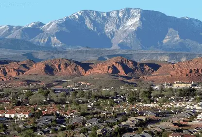 Snow-capped Pine Valley Mountain rising above the red sandstone bluffs and rooftops of Washington City, Utah — 84780 homeowners insurance with wildland-urban-interface exposure on the north edge of town