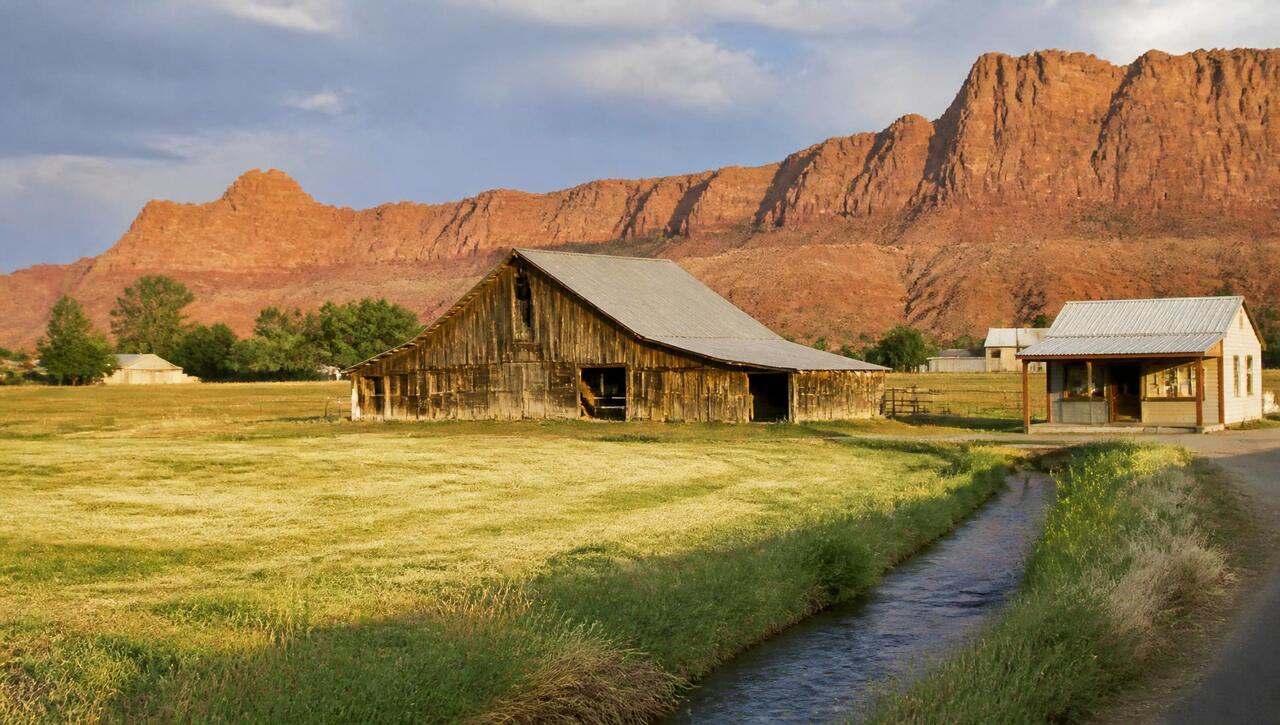 Weathered barn and small roadside business shed below the red Hurricane Cliffs in Kanarraville, Utah (ZIP 84742) — business insurance, BOP, general liability, commercial property and workers' comp for Kanarraville, Utah employers