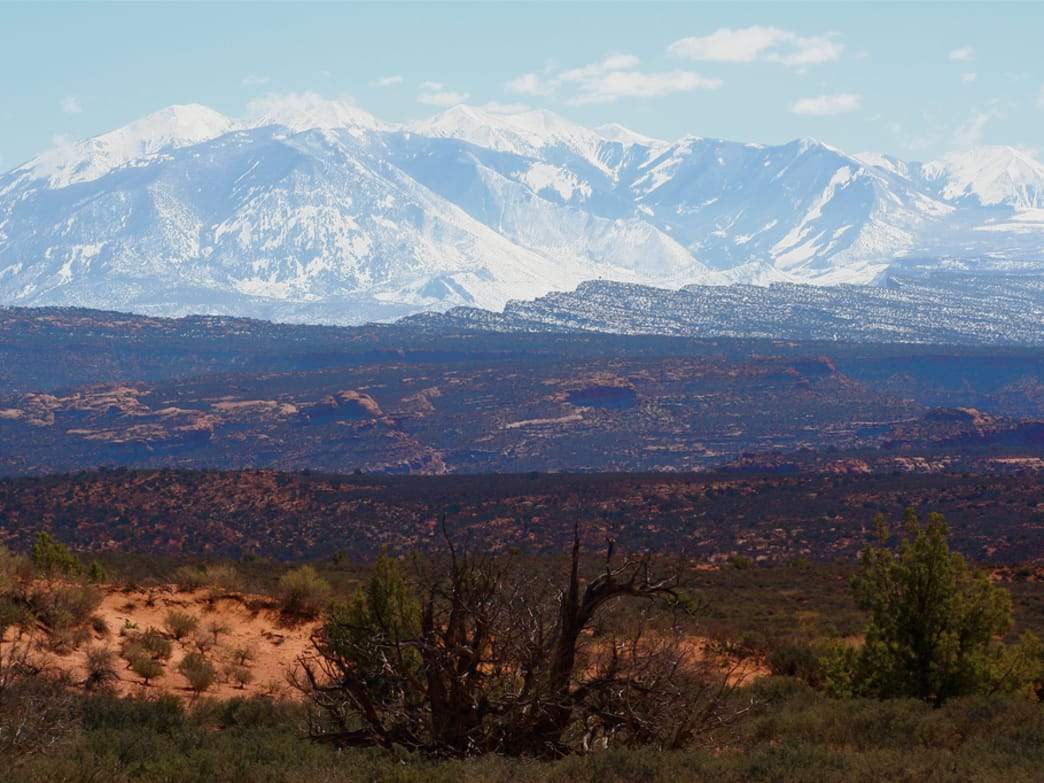 Snow-capped mountains rise above the red rock desert of Southern Utah
