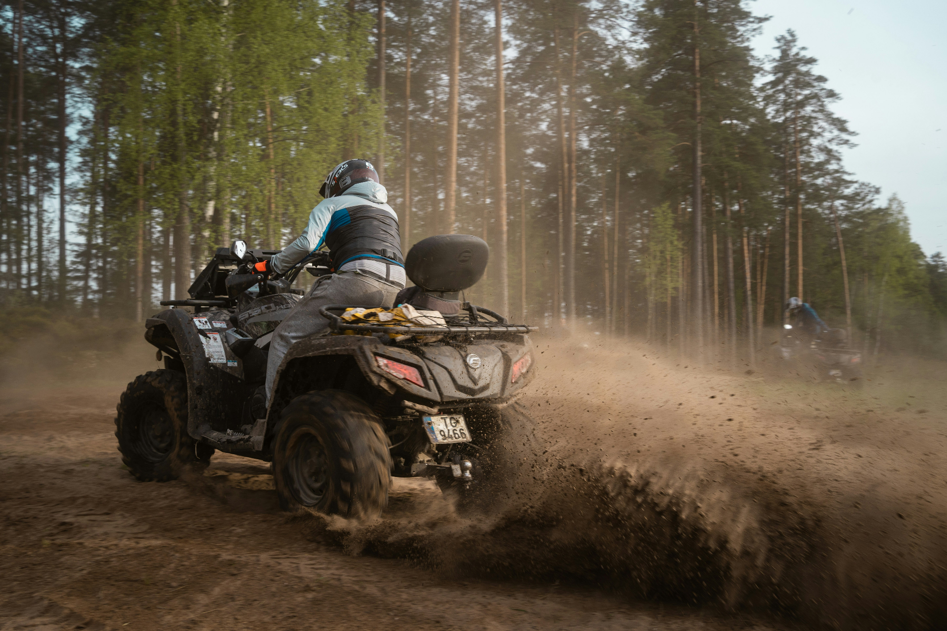 Can-Am ATV rider kicking up a dust cloud on a forest trail — Washington City UTV insurance with rollover and med-pay