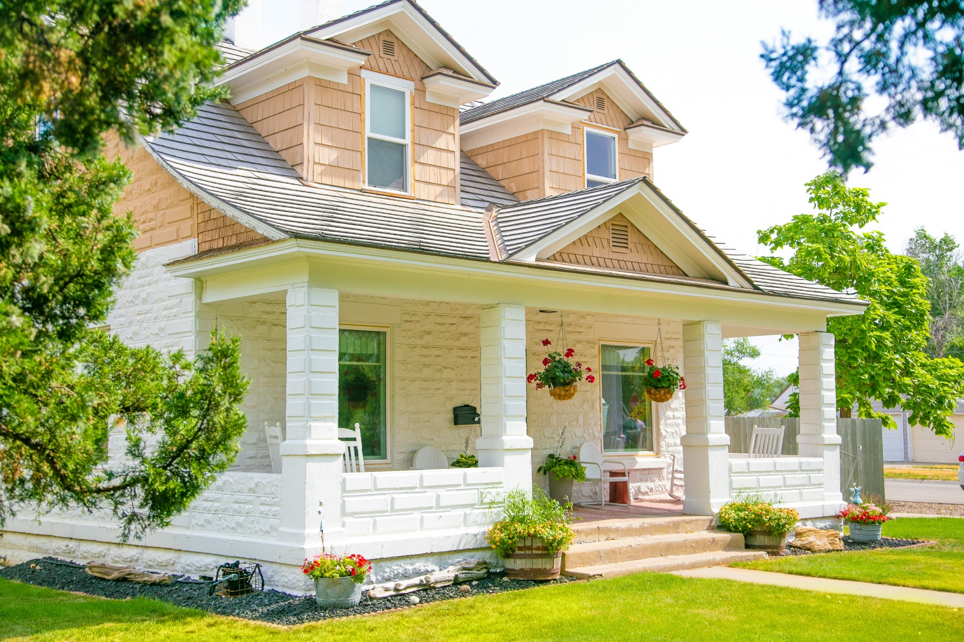 White cottage with wraparound porch and hanging planters — typical Kanab, UT owner-operated home