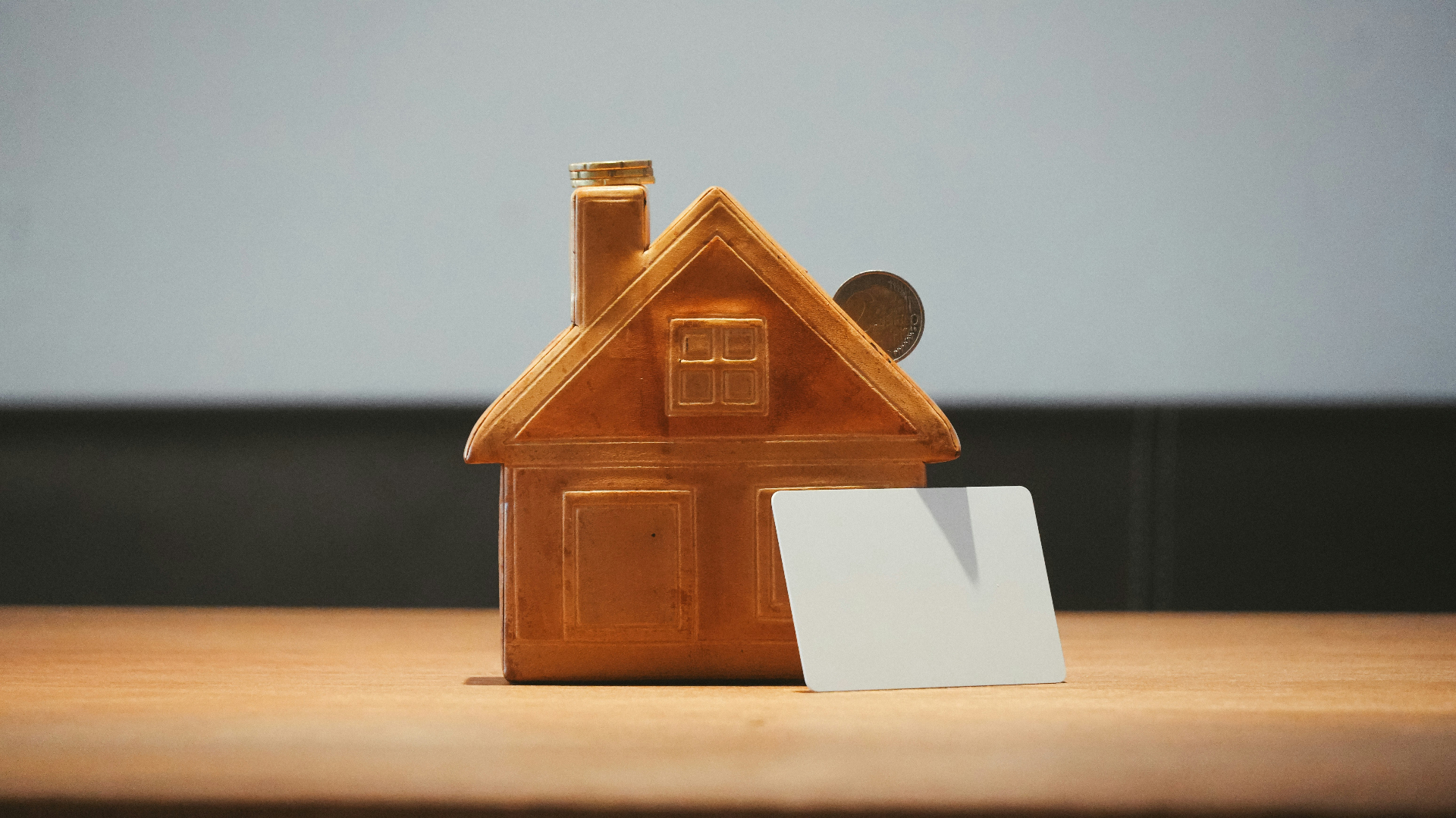 Copper house figurine beside a coin — home insurance replacement cost in St. George Utah