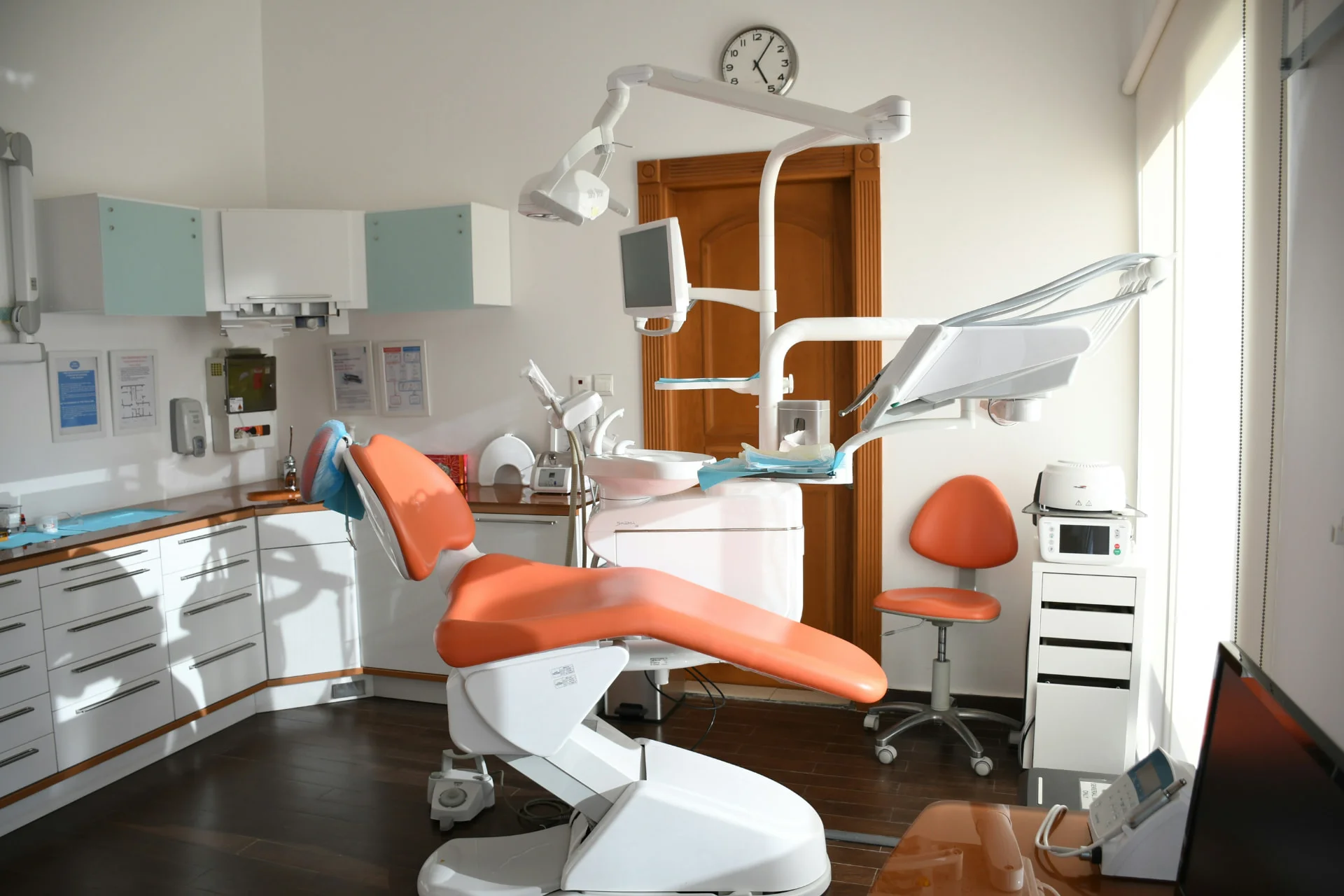 Bright, modern dental operatory with an orange patient chair and natural light