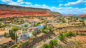 Hillside St. George homes set against red rock cliffs — foothill properties OnPoint underwrites for wildfire exposure.