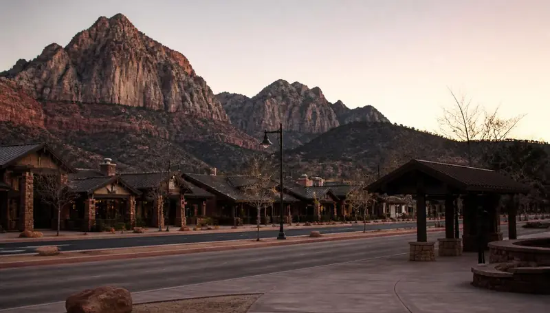 Springdale, Utah shops and shuttle stop at dusk with sandstone monoliths behind — health insurance and ACA Marketplace enrollment for Springdale, Utah 84767 households