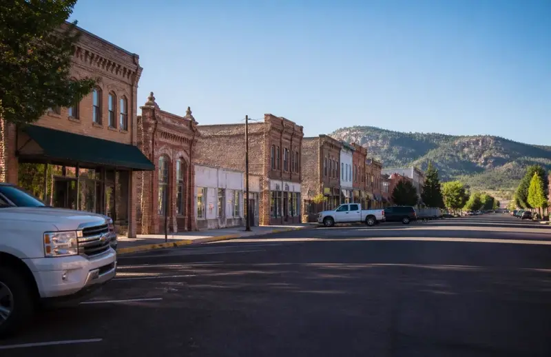 Red-brick pioneer storefronts along Main Street in Panguitch, Utah with forested plateau ridges behind — free ACA health insurance enrollment for Garfield County households in 84759