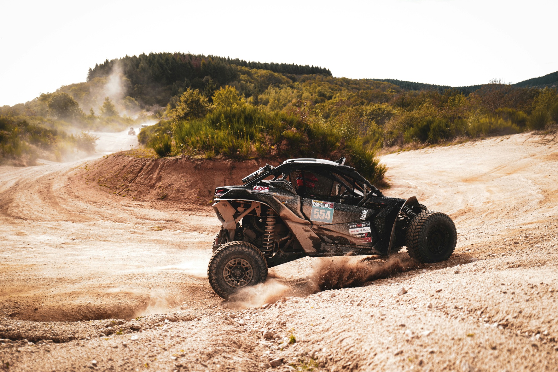Can-Am Maverick X3 UTV kicking up dirt on a dune-road curve — ATV and UTV insurance in Washington City, Utah 84780
