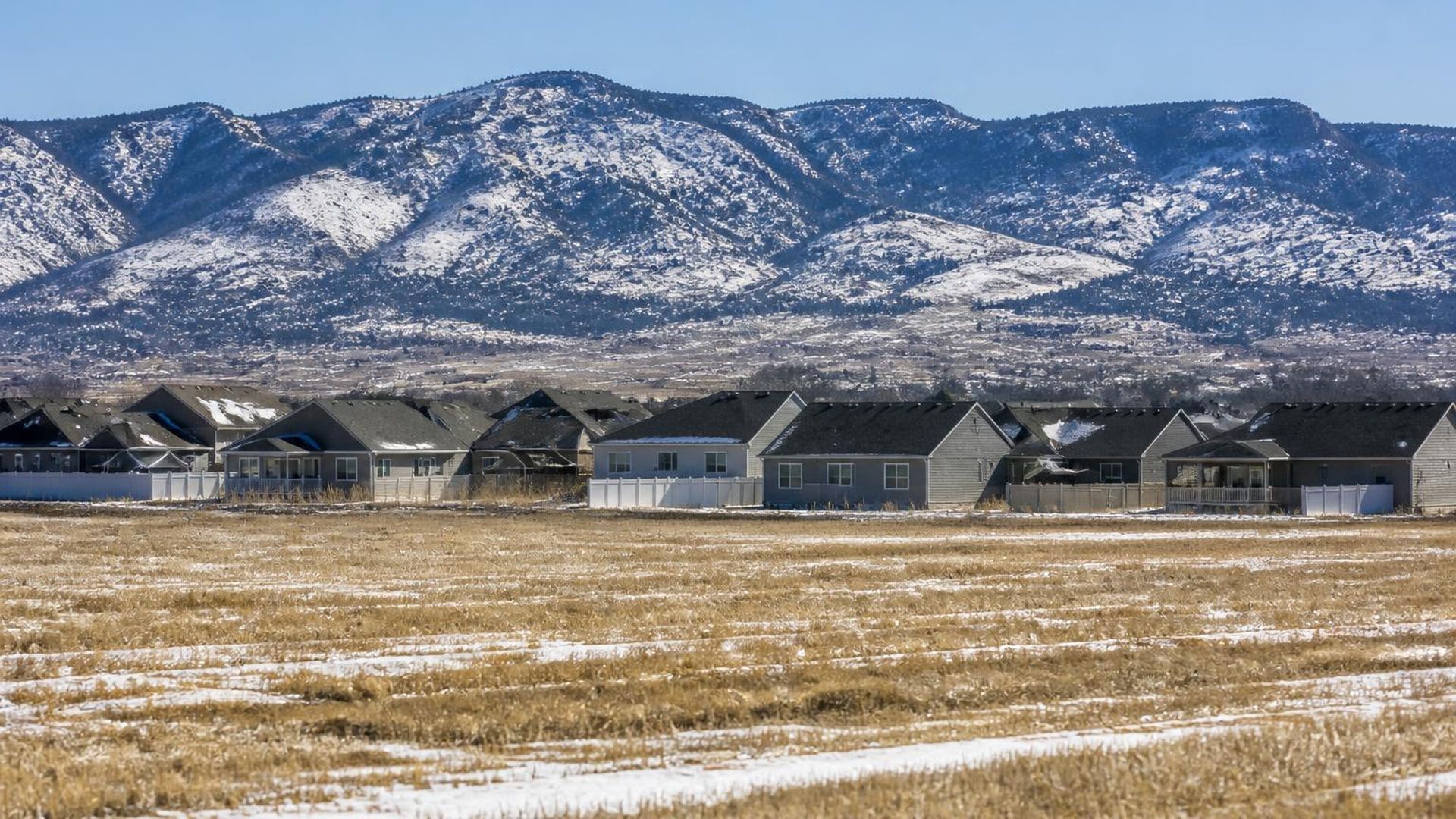 Newer homes at the edge of hay fields with snow-dusted peaks behind Enoch, Utah (ZIP 84721) — ACA / Obamacare Marketplace health insurance, subsidies and off-Marketplace plans for Enoch, Utah households