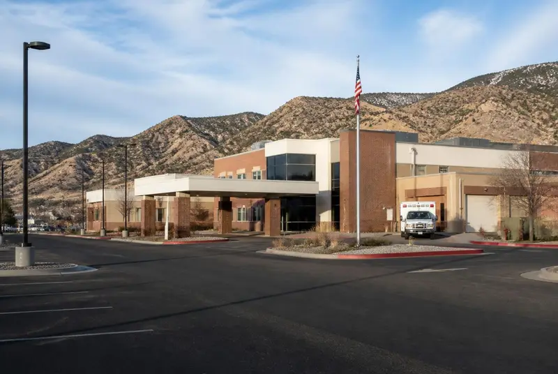 Regional hospital in central Utah with a covered emergency entrance and ambulance bay below dry mountain ridges — Sevier Valley Hospital anchors Richfield-area Marketplace networks