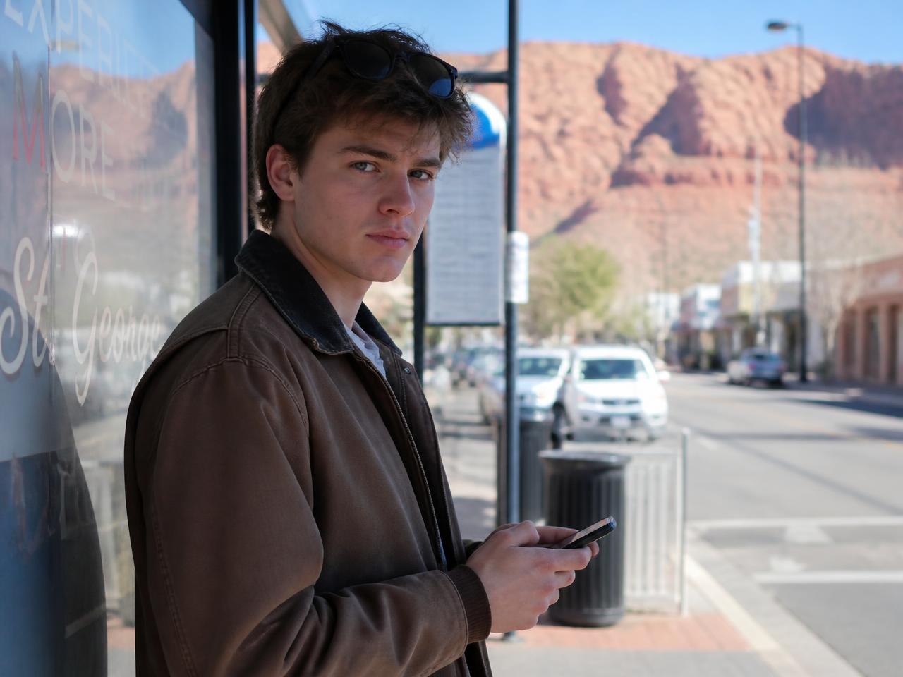 Young Utah driver at a bus stop after a license suspension, waiting to reinstate with a non-owner SR-22 policy