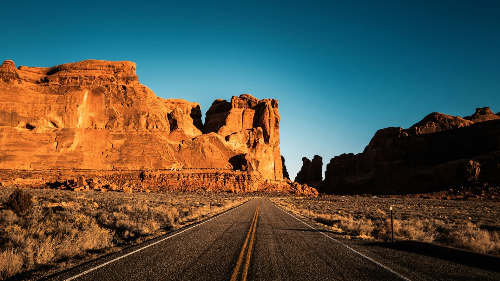 Desert road curving toward layered red rock cliffs and mesas near Santa Clara, Utah — ACA / Obamacare health insurance enrollment for 84765 families and owner-operated small businesses