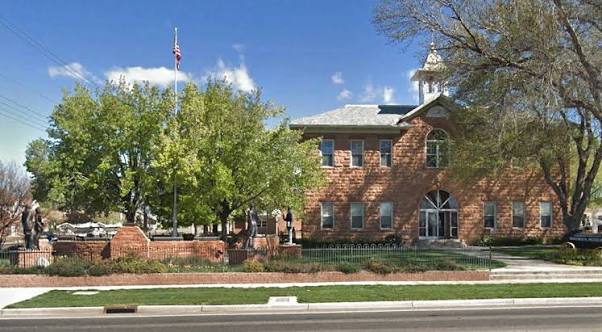 Historic brick building in Washington City, Utah with American flag and tree-lined grounds — car insurance for Washington City, UT drivers