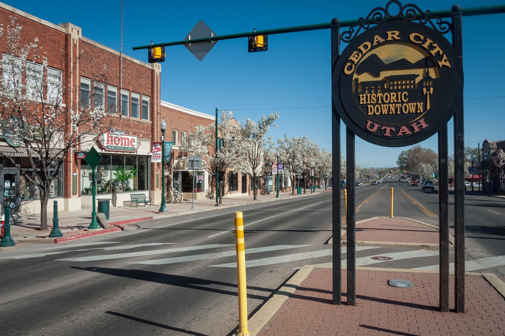Historic Downtown Cedar City, Utah sign on Main Street with red-brick storefronts and spring blossoms — auto insurance for Cedar City and Iron County drivers