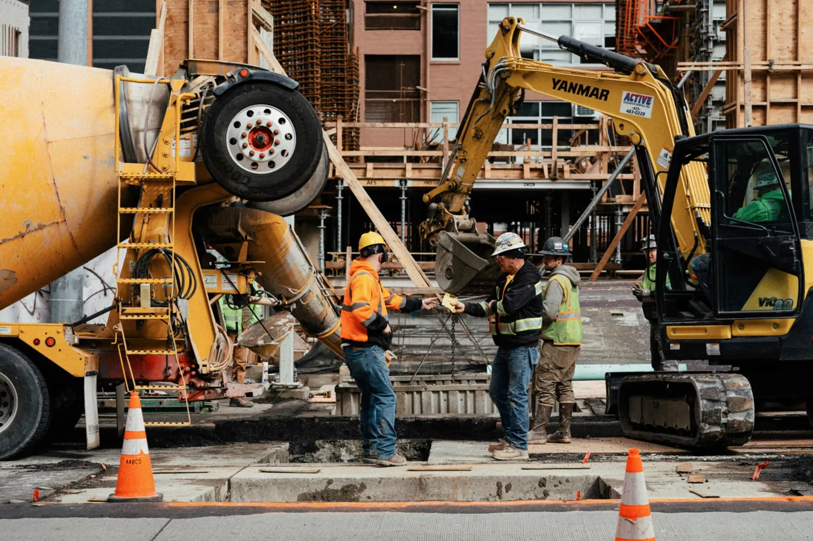 Concrete truck, excavator, and crew coordinating on a St. George, Utah commercial jobsite — contractors general liability and equipment coverage