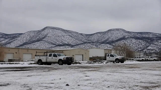 Light-industrial buildings and trucks under snow-dusted Iron County mountains in Cedar City, Utah — local commercial insurance risk factors for Cedar City, Utah 84720 businesses