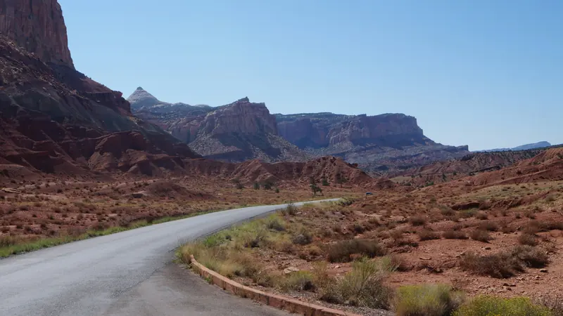 Quiet desert road winding beneath red sandstone cliffs and distant mesas near Santa Clara, Utah — 84765 ACA health insurance for families and owner-operated small businesses
