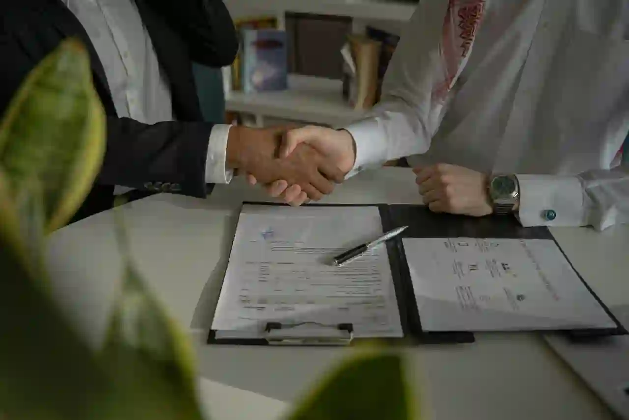 Local independent insurance agent shaking hands with a business owner over a signed policy