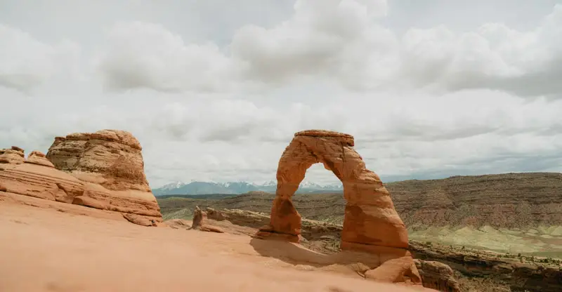 Delicate Arch in Utah red rock country under cloudy skies — Southern Utah ACA health insurance for St. George individuals, families, and self-employed