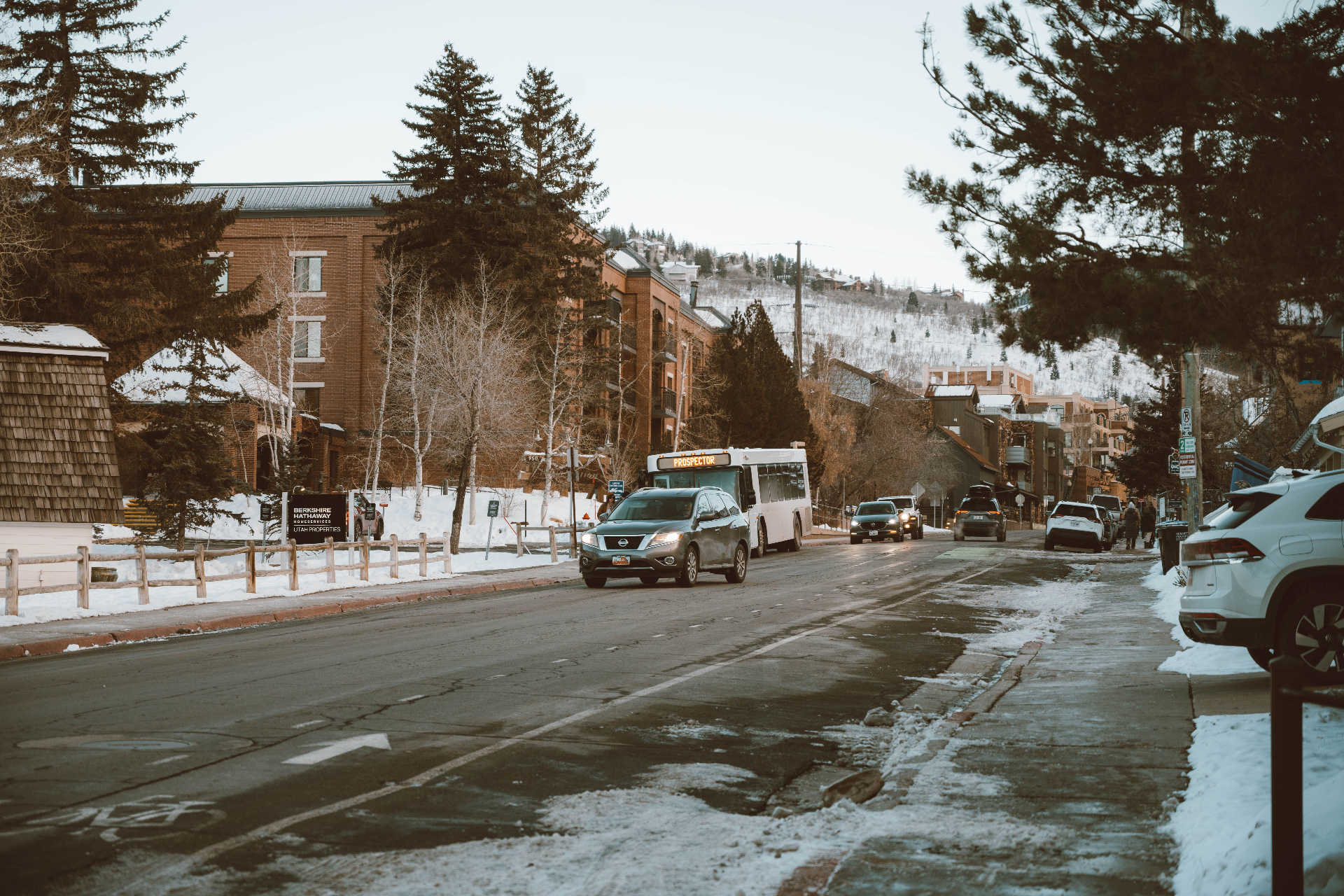 Snowy Utah mountain-town street in winter with slush and parked vehicles — the same winter weather that puts Cedar City homeowners at risk of roof collapse, ice-dam leaks, and burst-pipe interior water damage