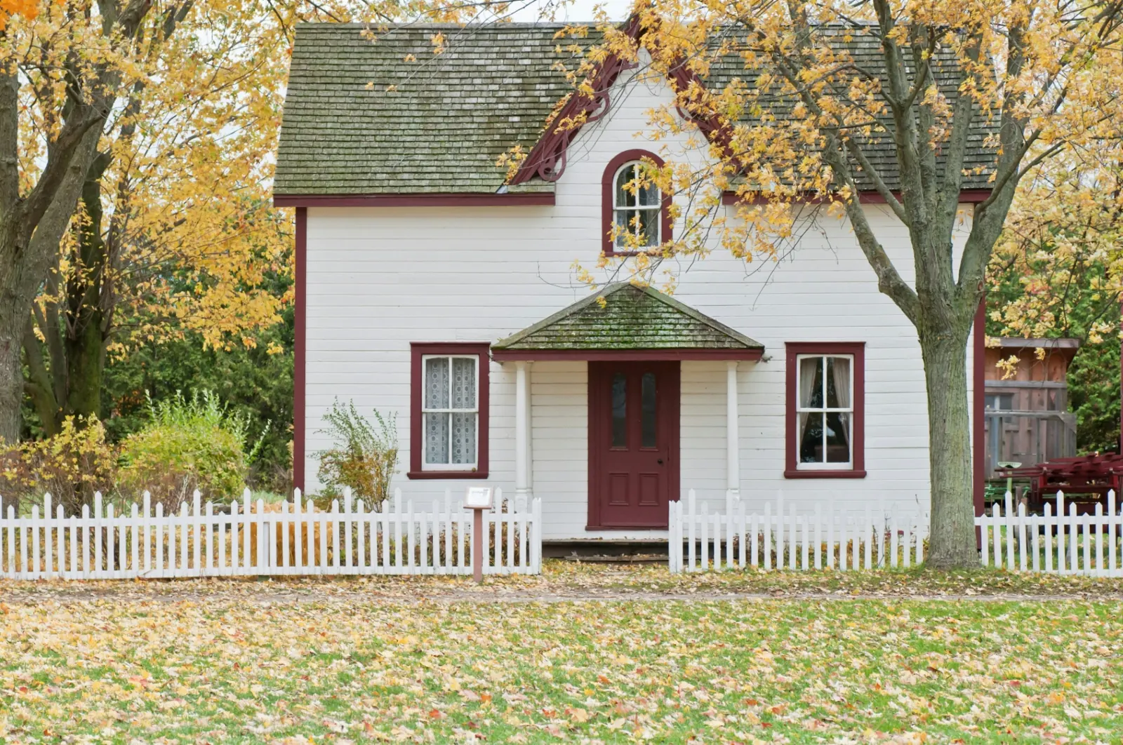 White farmhouse with maroon trim and defensible-space landscaping — Southern Utah wildfire-resistant home
