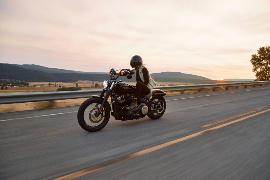 Rider on a Harley-Davidson cruising an open highway at sunset