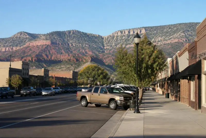 Historic Main Street storefronts in Cedar City, Utah with the red-rock foothills behind — free ACA health insurance enrollment for Iron County households in 84720 and 84721