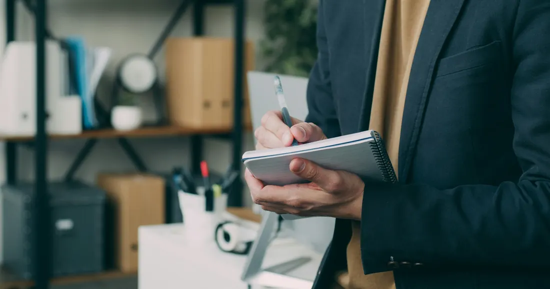 Business owner writing in a notebook while planning insurance coverage