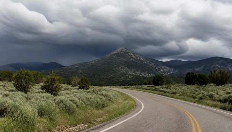 Rural road curving through sagebrush toward pine-covered peaks near New Harmony, Utah — health insurance and ACA Marketplace enrollment for New Harmony, Utah 84757 households