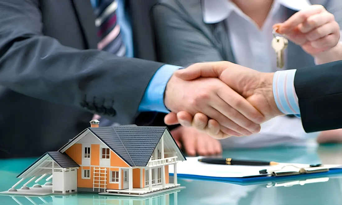 Insurance agent shaking hands with a client over a model home