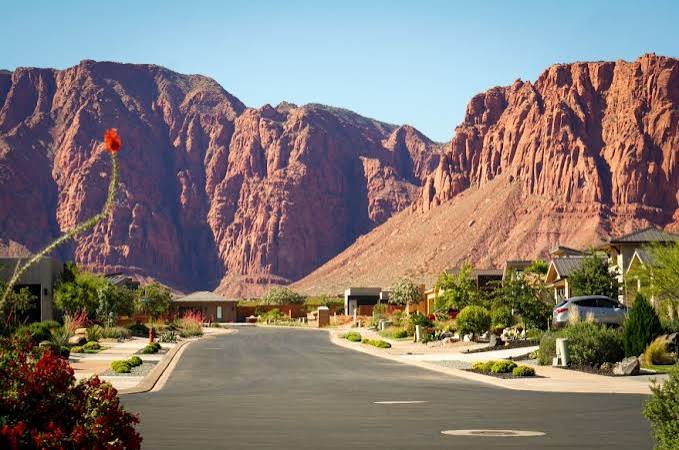 Quiet Kayenta residential street in Ivins, Utah backed by red sandstone cliffs