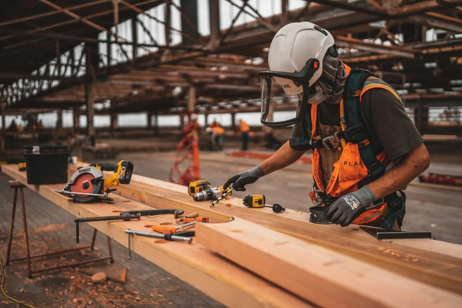 Contractor in high-visibility gear working on a timber beam at a Southern Utah job site
