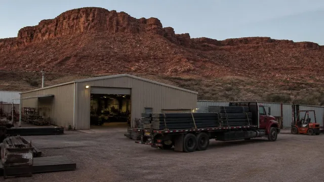 Small fabrication shop and flatbed truck below the red canyon ridge in Kanarraville, Utah — local commercial insurance risk factors for Kanarraville, Utah 84742 businesses