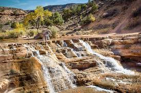 Cyclist riding above the multi-tier travertine cascades at Toquerville Falls outside Toquerville, Utah in autumn — the off-road and side-by-side traffic on Toquerville Falls Road that personal auto policies often exclude