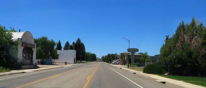 Enterprise, Utah Main Street on a clear day looking toward the center of town with the white Enterprise landmark building and historic storefronts along SR-18 in 84725.