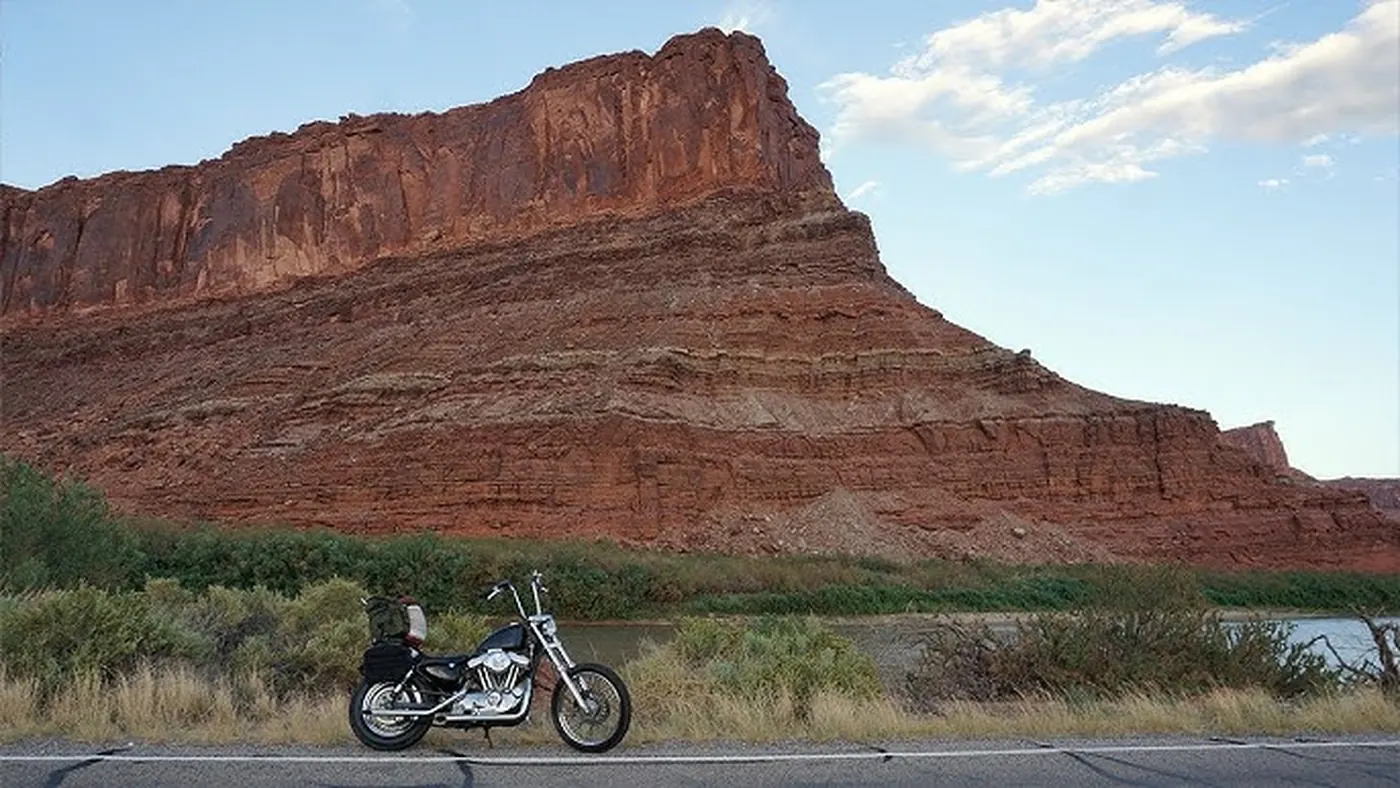 Harley-Davidson Sportster parked along the Colorado River with red rock cliffs above near Moab, Utah