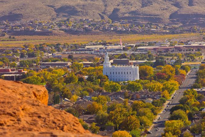 St. George, Utah skyline with the LDS temple framed by red rock cliffs and autumn cottonwoods