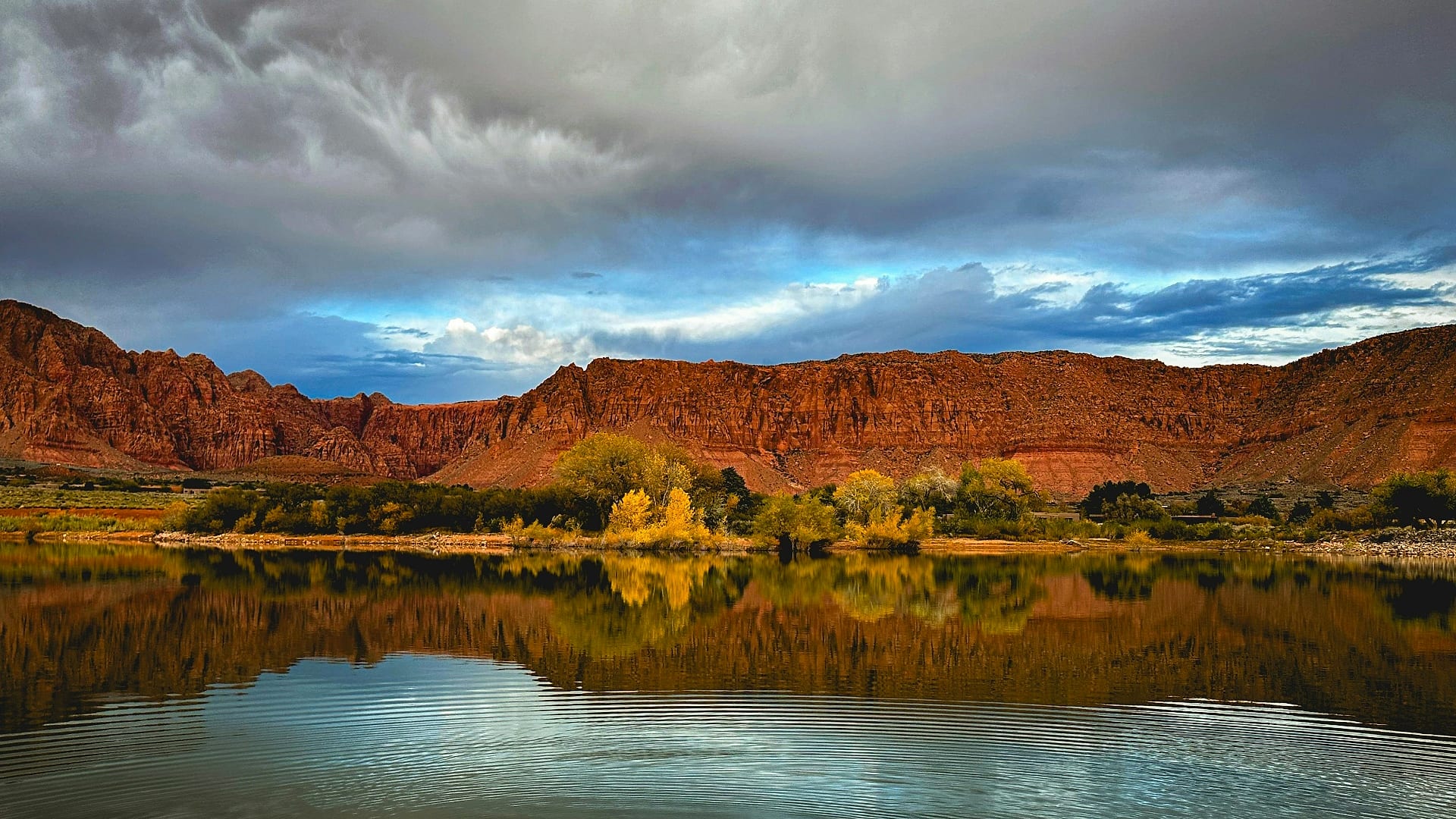 Red sandstone cliffs of Kayenta and Snow Canyon reflecting in a calm reservoir near Ivins, Utah — auto insurance for Ivins drivers