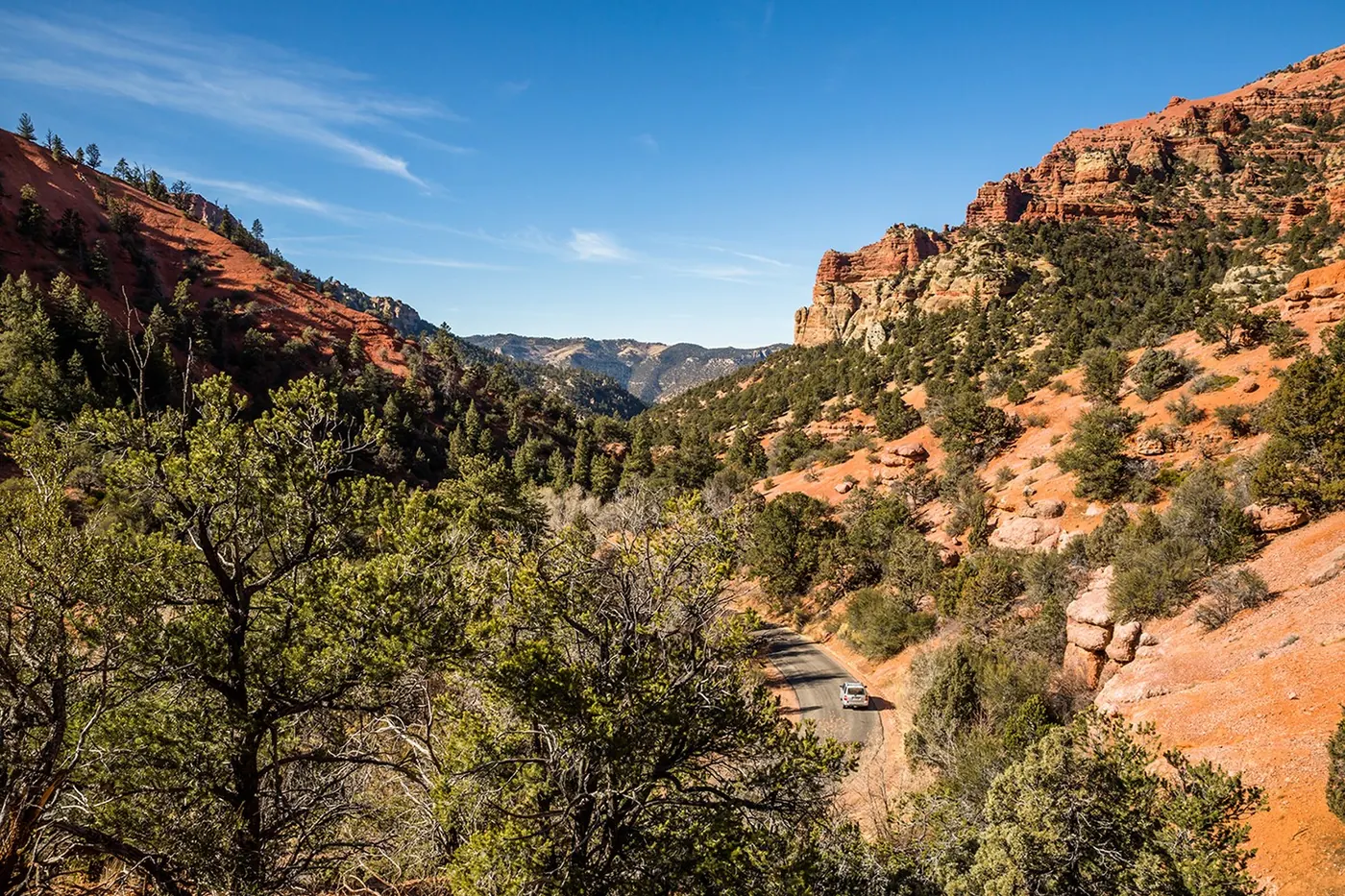 Vehicle driving the winding SR-14 Cedar Canyon road above Cedar City, Utah — the Brian Head and Cedar Breaks route that drives winter car insurance pricing in 84720 and 84721
