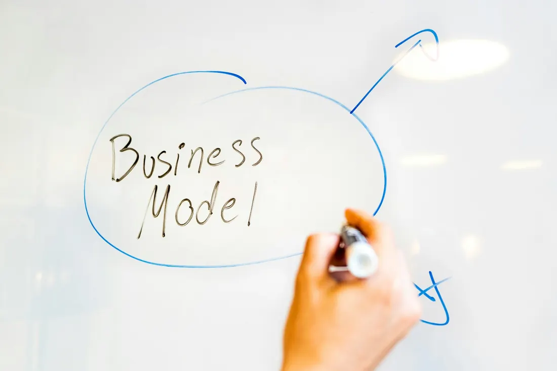 Business owner mapping out a business model on a glass whiteboard